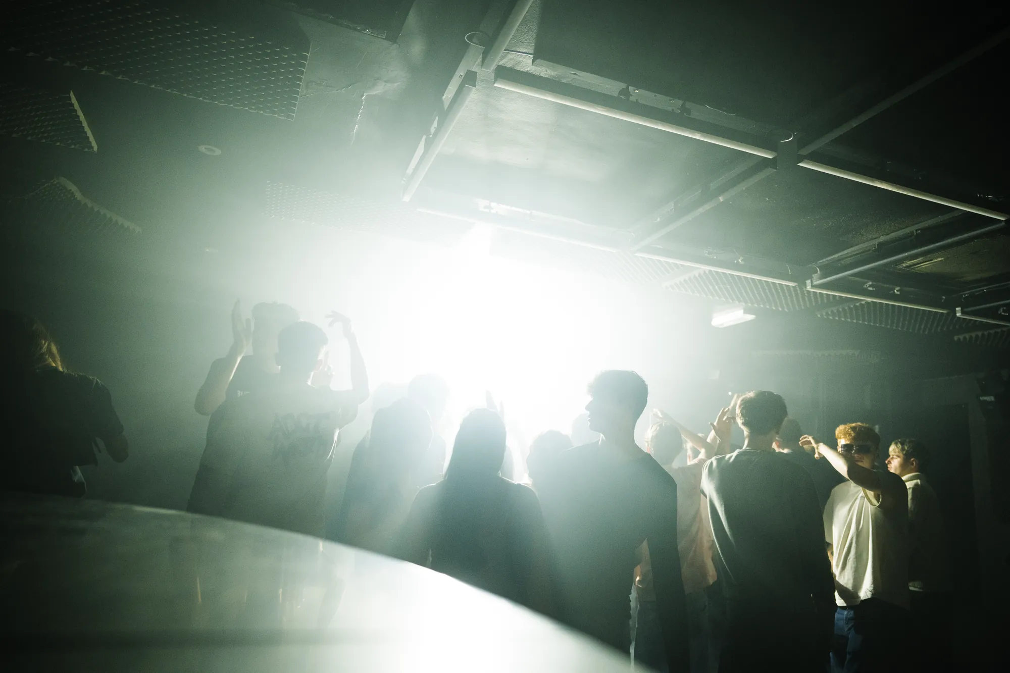Crowd silhouetted against haze and a white stage light at Citrus 001